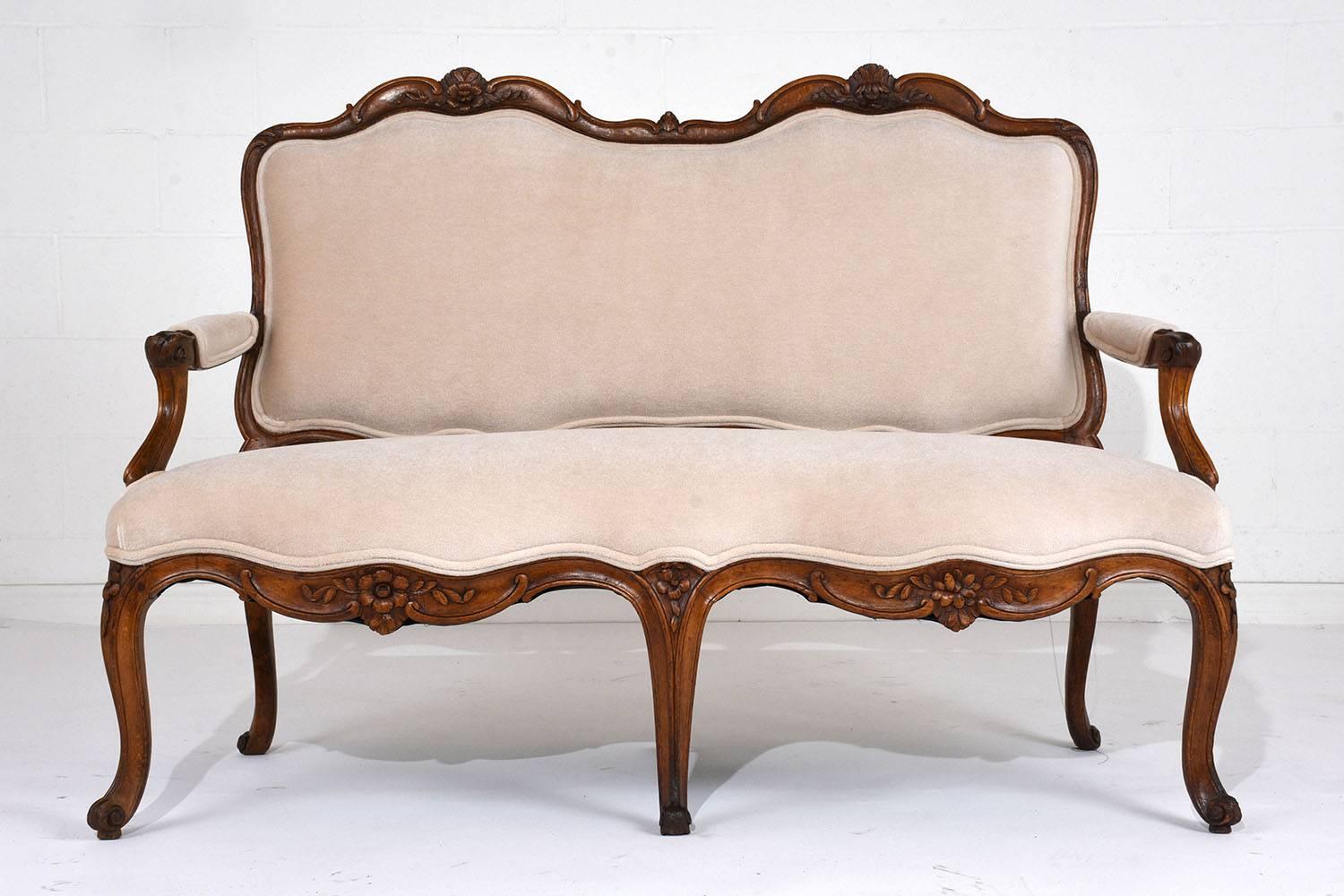 This Antique 18th Century Louis XV-Style Sofa has a hand-carved frame made of walnut wood finished in its original rich walnut color stain finish and has been professionally restored. The settee is ornately adorned with six different handcrafted