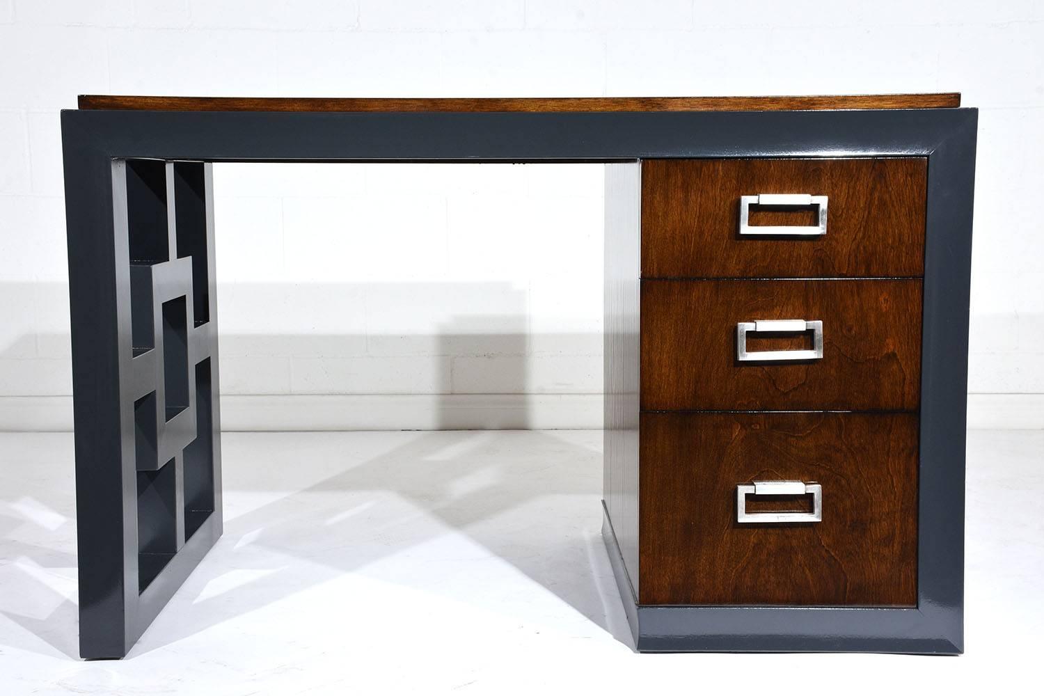 This 1960’s Mid-Century Modern kneehole desk is artfully finished in two complementary tones of a slate gray and rich walnut color. The top and pedestal drawers are finished in a walnut color with a beautiful natural patina. There are two