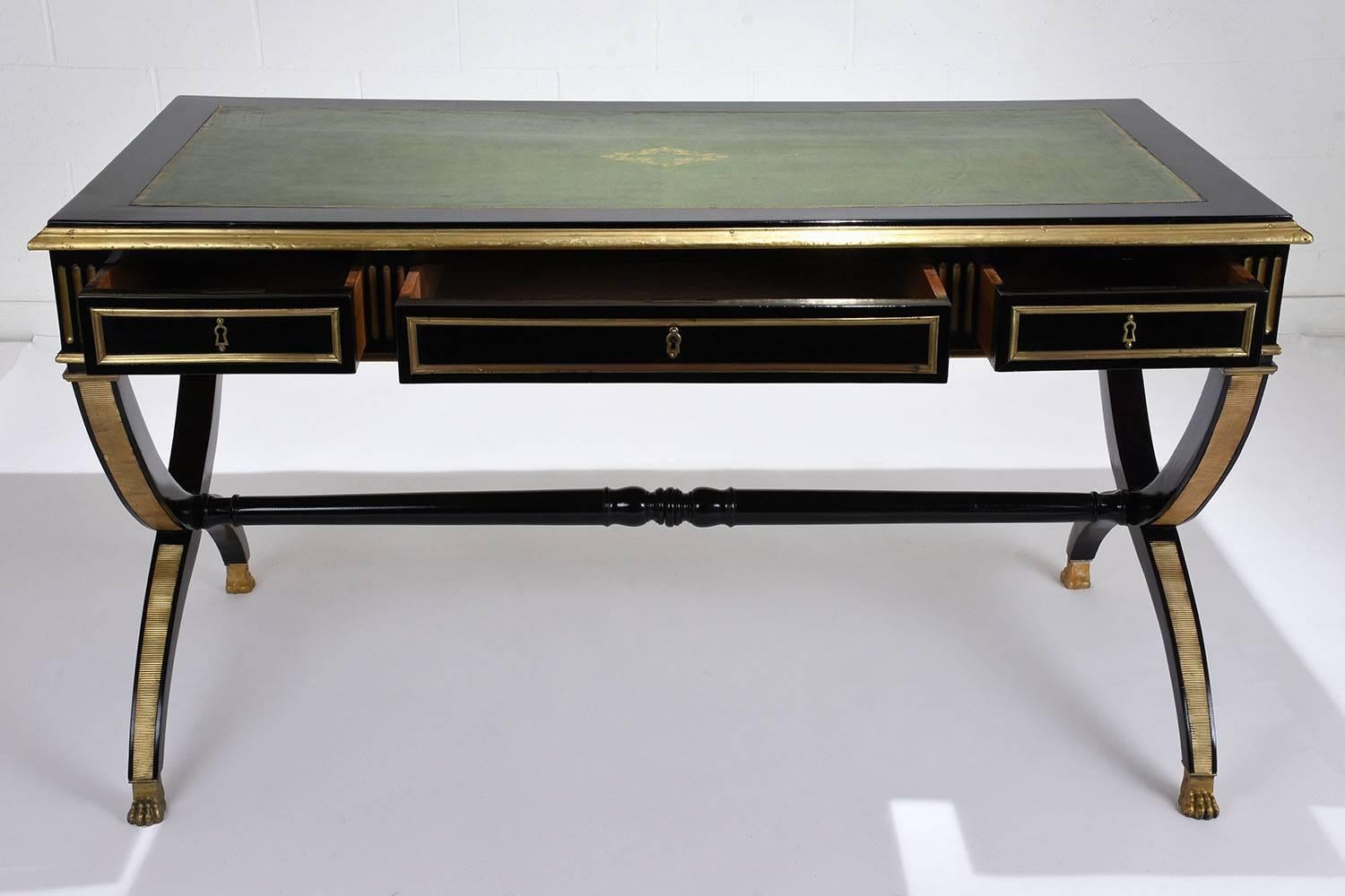 This 1900s French Empire-style desk is made of mahogany wood ebonized in a rich black color with a lacquered finish. The desk has two leaf extensions on either side that allow for a larger work space. Both the top and leaves are adorned with