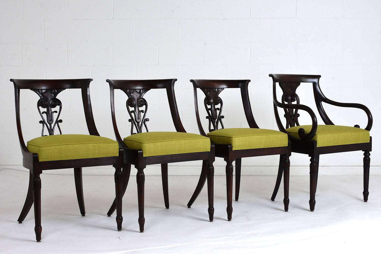 This Antique Set of Four Hollywood Regency-style Dining Chairs has been handcrafted out of mahogany wood stained in deep mahogany color with a polished finish and is fully restored. The set features three side chairs, an armchair, and the seats have