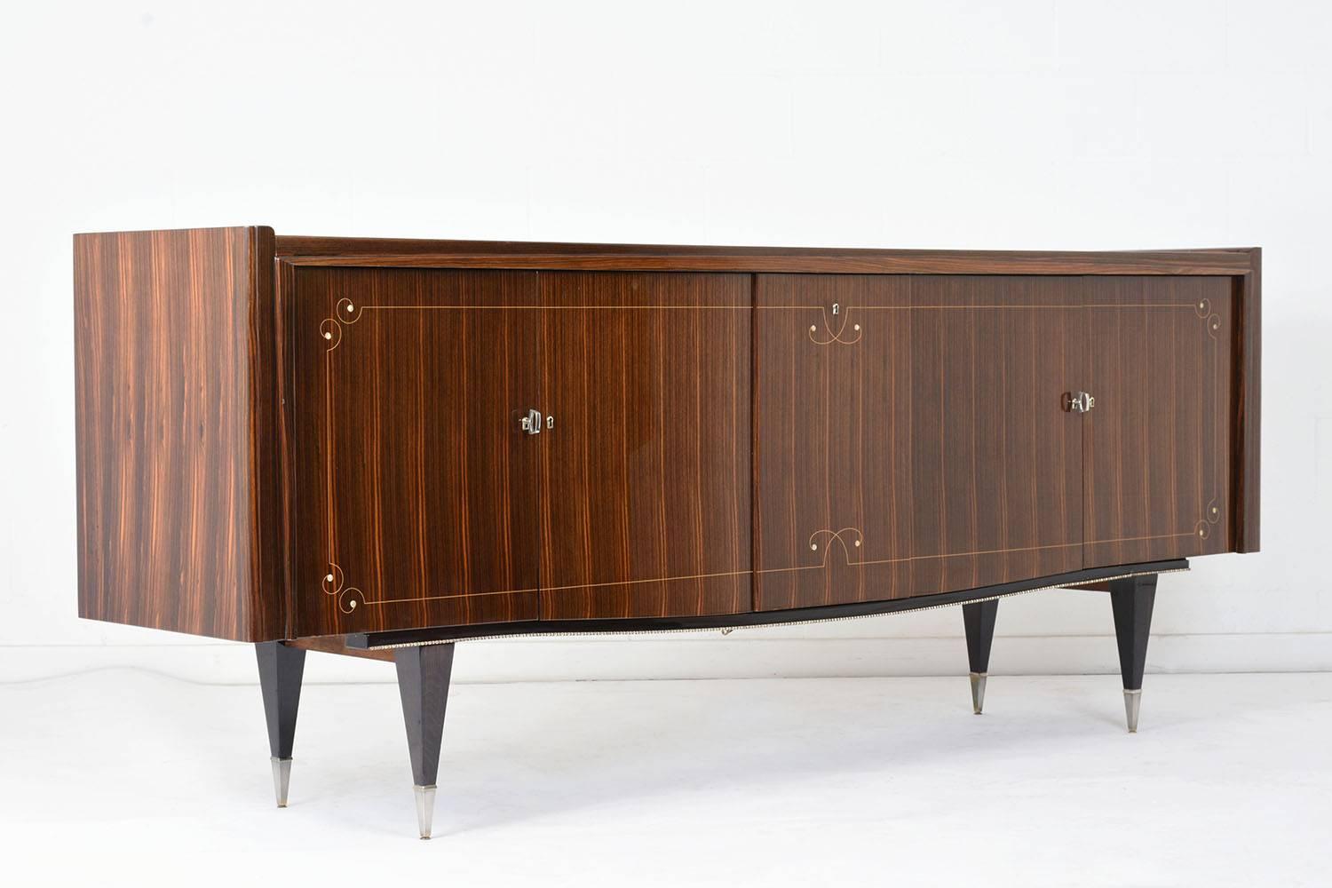 This 1940s French Mid-Century Modern-style buffet is made of wood covered in Macassar ebony veneers in a rich rosewood colored stain with a lacquered finish. The facade of the cabinets have delicate mother-of-pearl inlay and scroll details. Inside