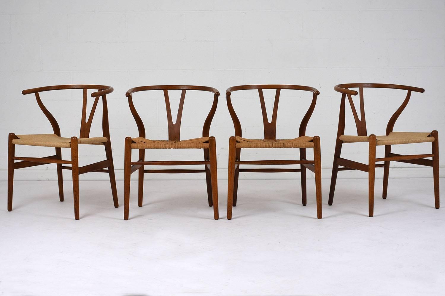 This set of four 1970s Mid-Century Modern-style dining chairs feature teak wood frames stained in a light walnut color and a polished finish. The horseshoe backs have a V-shaped splat and serpentine arms. The round tapered legs have stretched bars