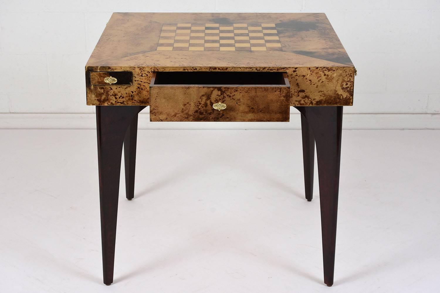 This 1980's modern-style game board is designed by Aldo Tura and is made of wood. The top of the table is covered in a unique goatskin parchment with an inlaid chess board in the center. There are two drawers on opposite sides of the table for