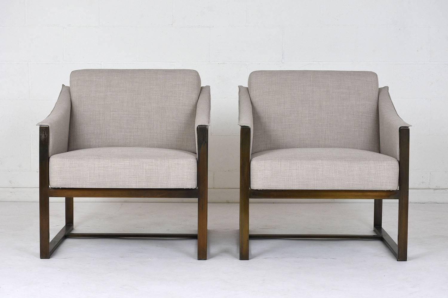 This pair of 1960s Mid-Century Modern-style lounge chairs is designed by Milo Baughman. The chairs feature geometric brass frames have curved arm rests and stretched legs. The comfortable seats have been completely restored with new upholstery and
