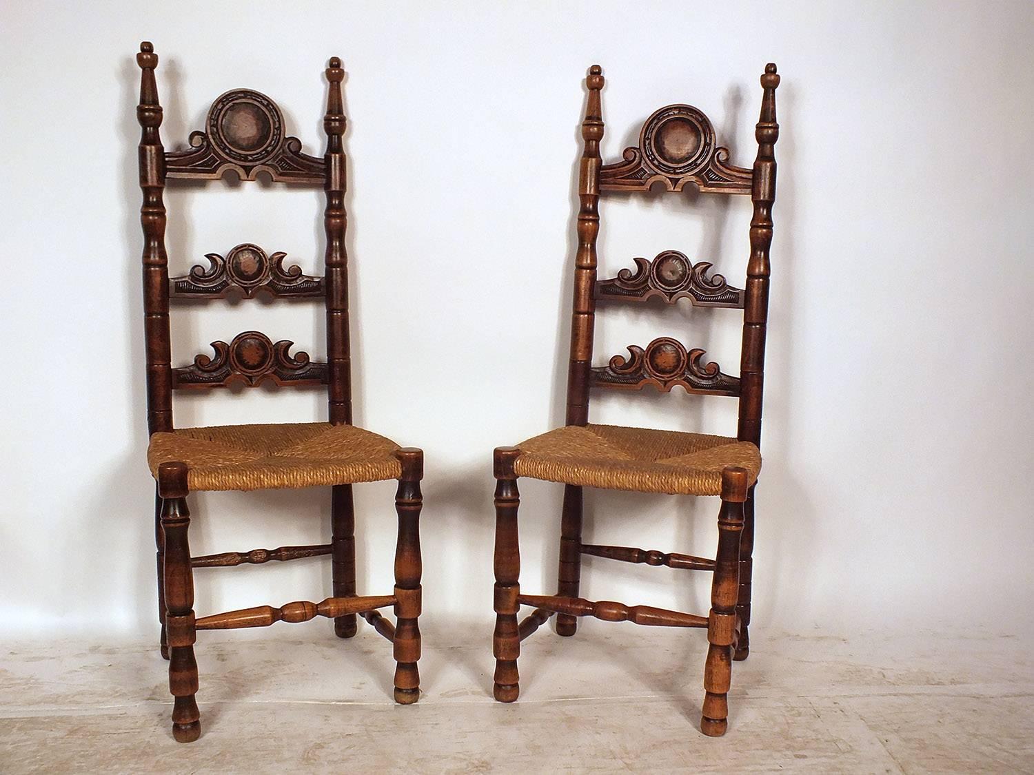 This set of eight 1900s French Provincial-style dining chairs feature a wood frame stained in a walnut color with a lacquered finish. The ornately carved frames feature a ladder-back design with a large centre crest and carved legs. The comfortable