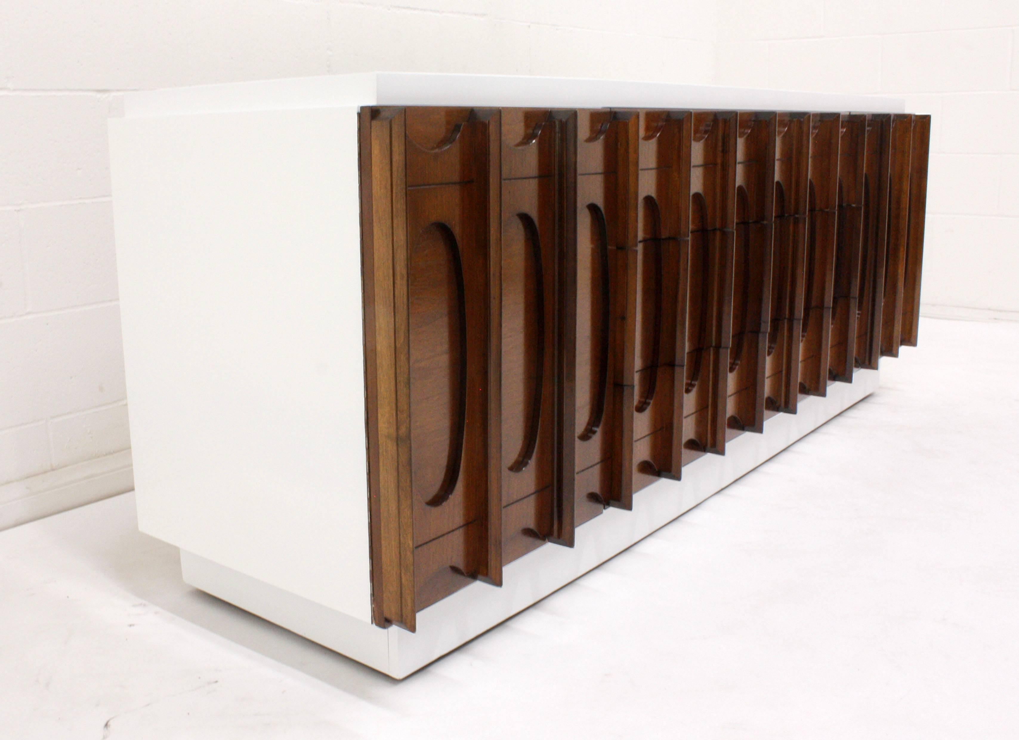 This 1960s Mid-Century Modern style credenza has been completely restored and is finished in a two-tone color combination with a lacquered finish. The top, sides, and bottom of the credenza is finished in a stark white and the cabinet doors and