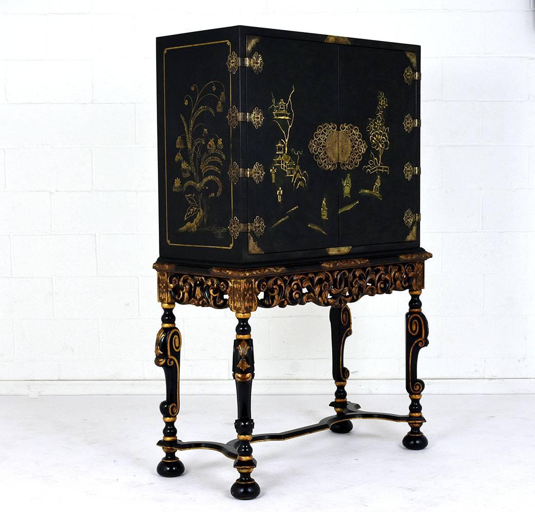 This 1930s chinoiserie-style dry bar is made of wood with an ebonized color and polished finish. The cabinet is adorned with landscape scenes of gardens, homes, and farms. The cabinet doors have ornate brass hinges, corner accents, and a large