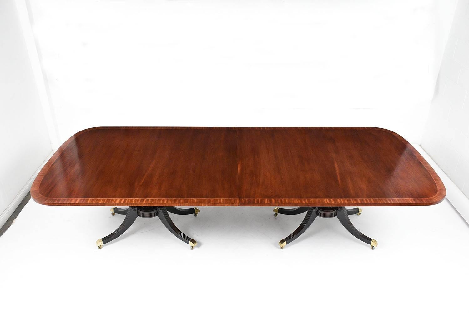 This 1980s Regency-style dining table is a special edition made by Baker Furniture Company. The dining table is made of mahogany wood stained in a rich mahogany color with a polished finish. The top of the table features an inlaid marquetry boarder