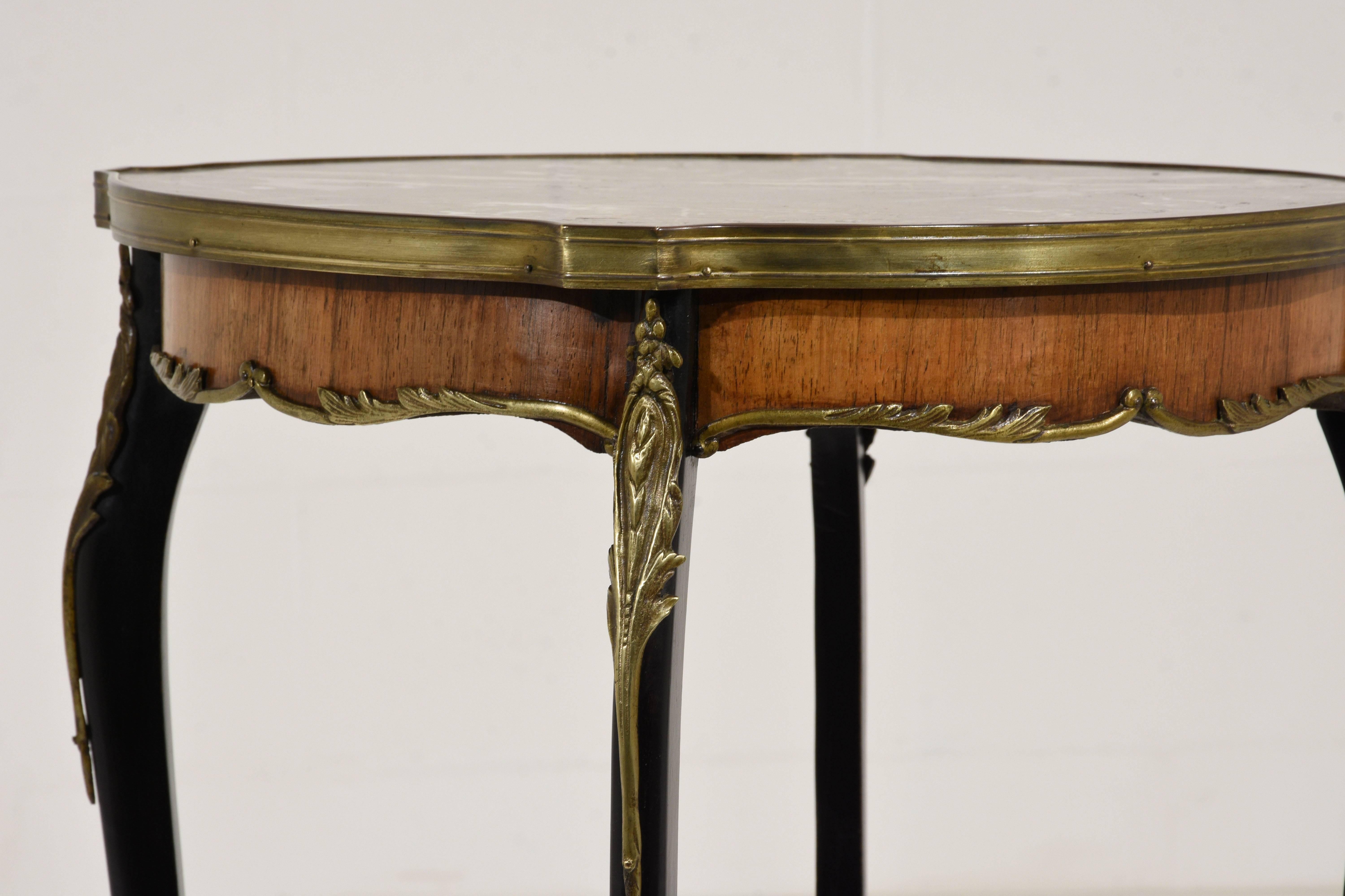 This 1900s antique French Louis XV-style side table is made of mahogany wood stained in a rich mahogany color on the edges and the open shelf. The top of the table is made from a rouge color marble with white veins and is surrounded by brass