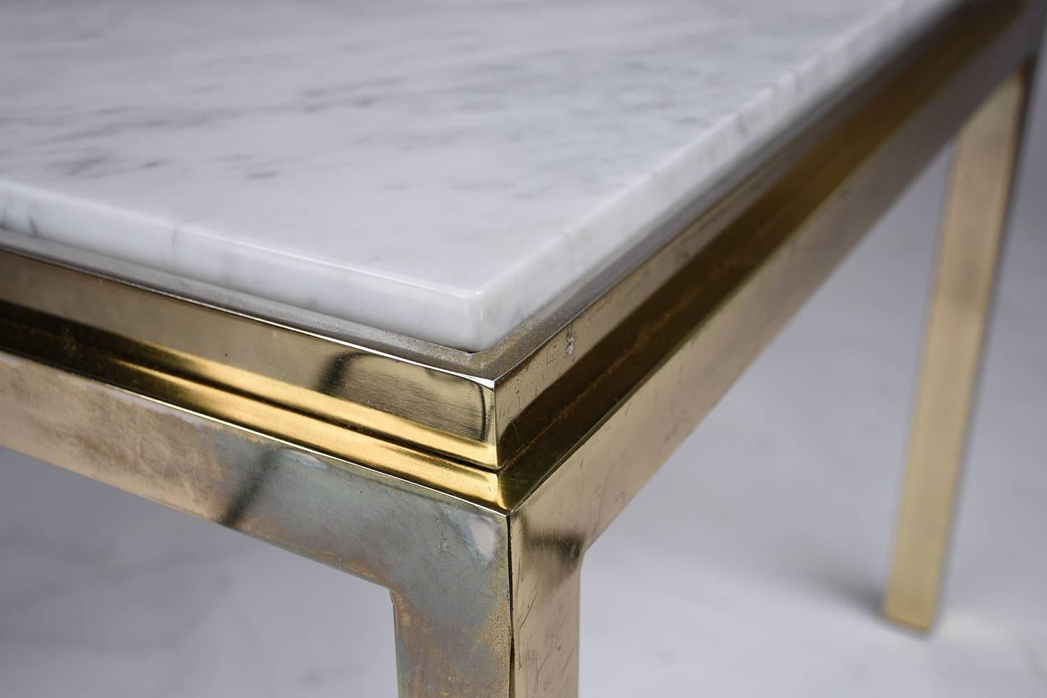 This 1970s vintage modern-style square coffee table features a brass frame and marble-top. The simple brass frame is slightly faded but is accentuated by the white Carrara marble top with a flat polish. This coffee table is sturdy, stylish, and