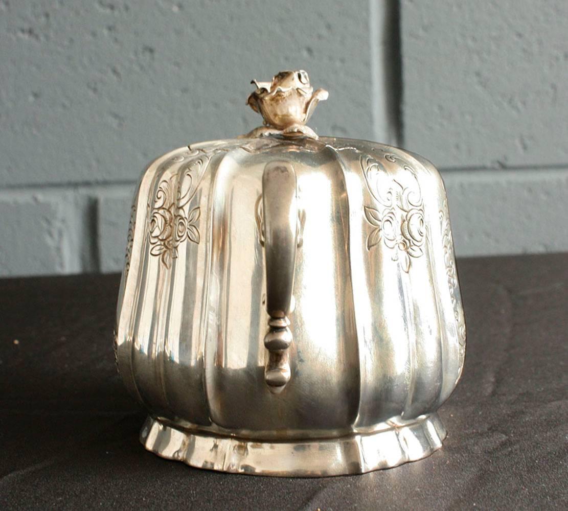 This 1900s English Traditional-style sugar dish is made of sterling silver and stamped .800. The sugar dish is adorned with etched floral, leafy and scroll details. The handles have scroll accents. The lid is adorned with a sculptural rose. The