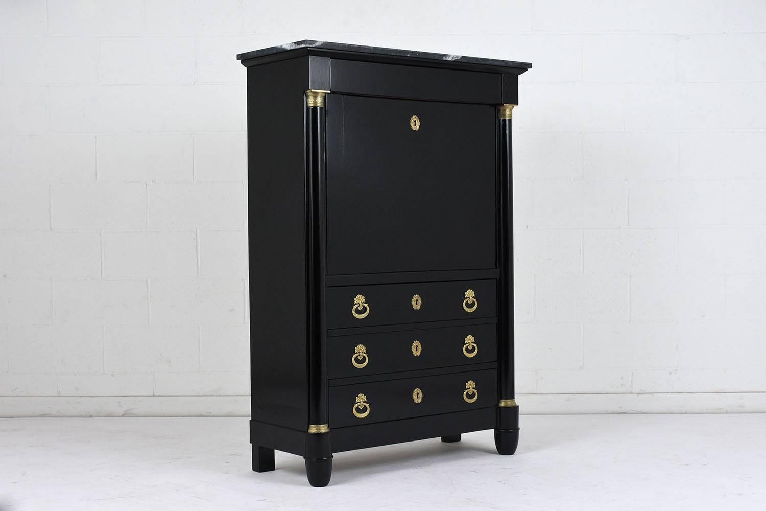 This 1890s French Empire style secretaire is made of wood stained in a deep black color with a lacquered finish. At the top of secretaire is a small drawer with three larger drawers below the desk. The drawers have decorative brass drawer pulls and