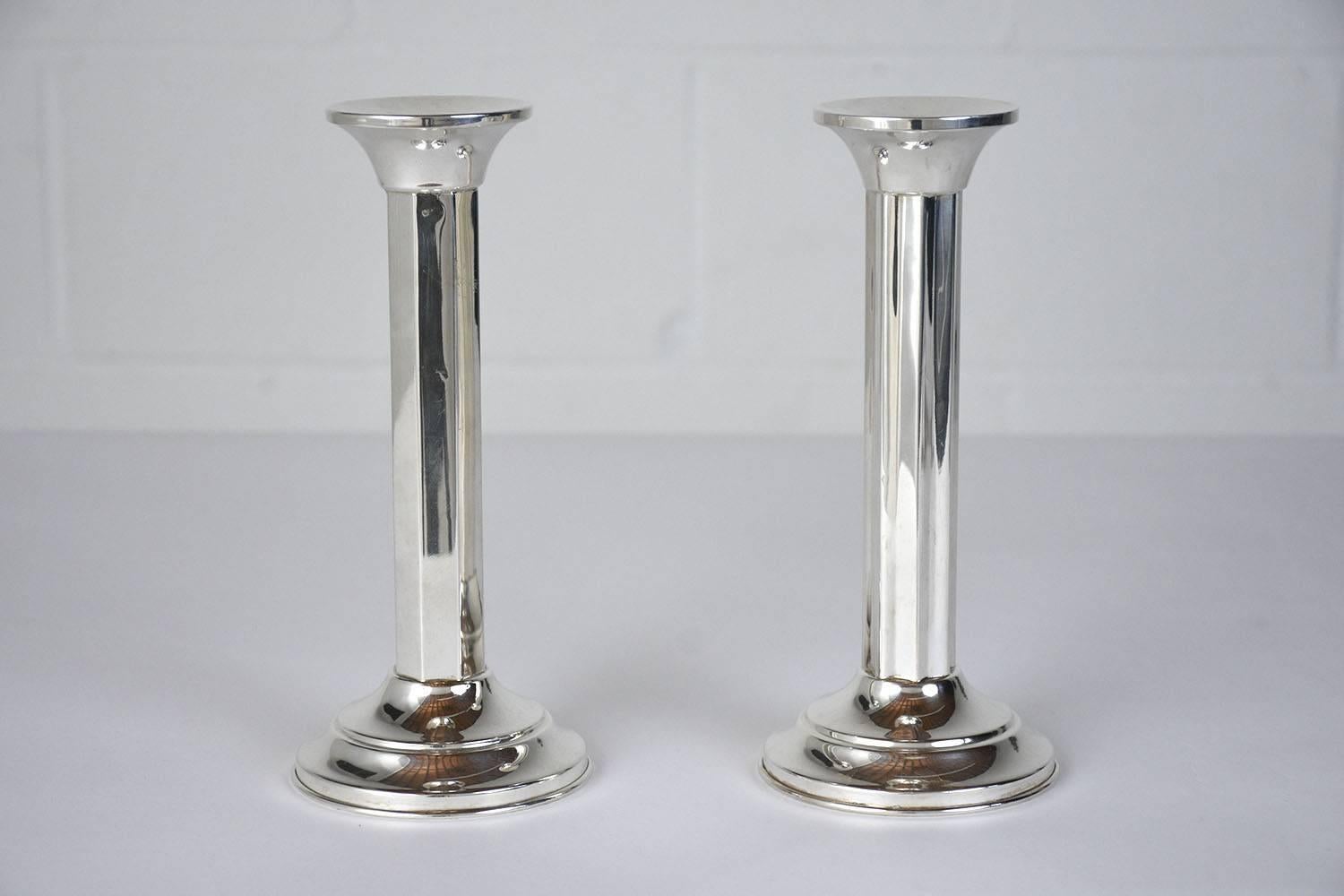 This pair of 1920s Art Deco-style candleholders are made from sterling silver stamped .800. The candle holders have a Classic design with faceted sides and a rounded base. This pair of candleholders is sturdy, elegant, and ready to be used in any