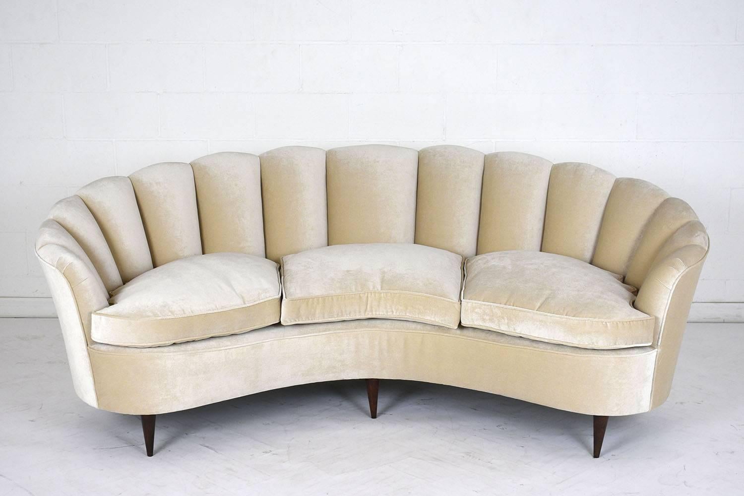This 1930s Hollywood Regency-style sofa is made in the manner of Gio Ponti. This sofa has a curved frame and the back of the seat features a scalloped deign with different sized cushions and a curved front edge. The sofa has been completely restored
