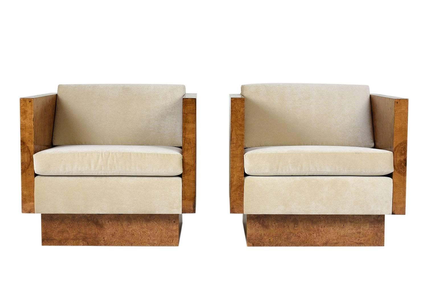 This pair of 1960s Mid-Century Modern cube lounge chairs is designed by Milo Baughman for Thayer Coggin. The sides and base of the lounge chairs are covered in burled wood in a mid-wood tone stain and a lacquered finish. The comfortable seats have a