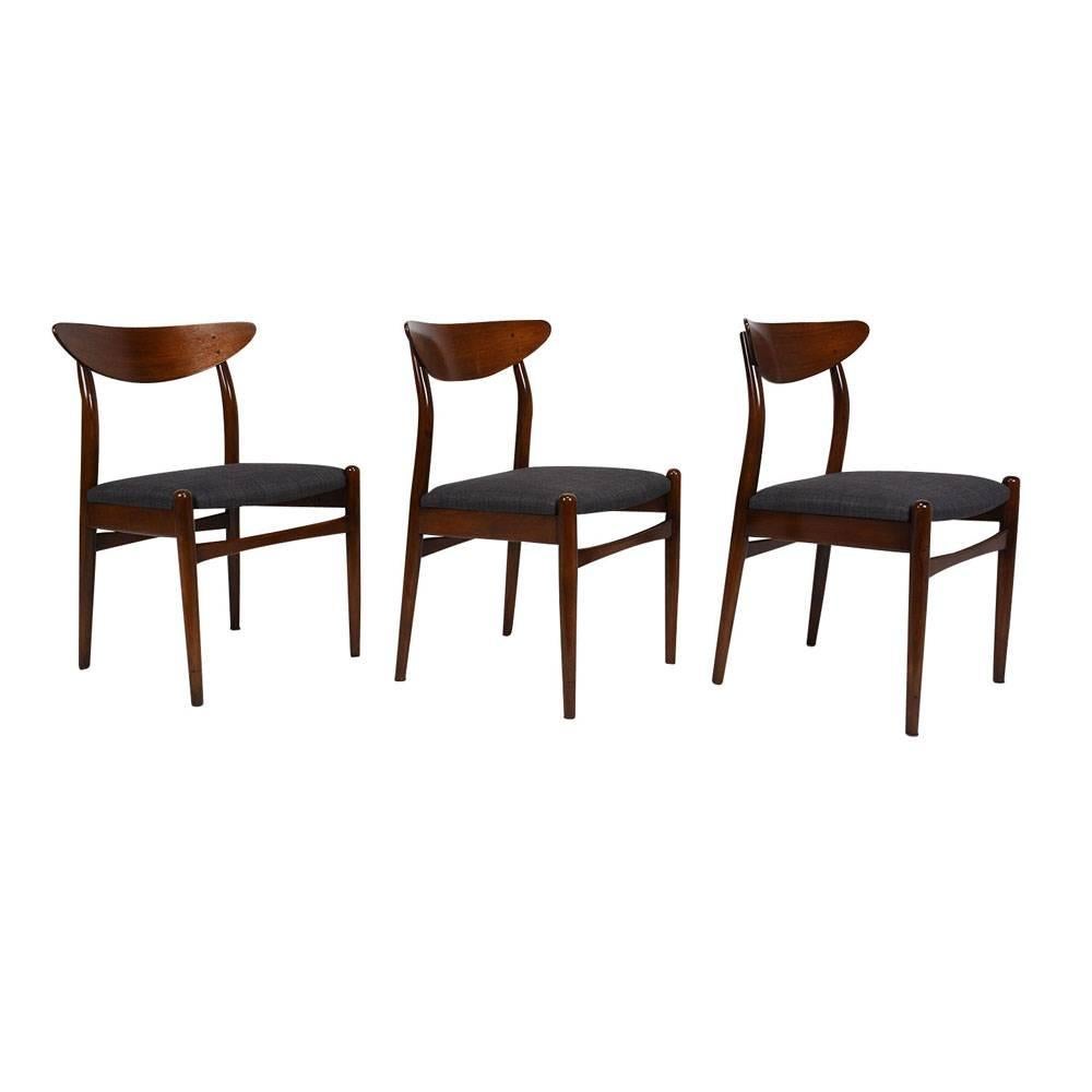 This set of six 1960's Danish Mid-Century Modern-style dining chairs feature teak wood frames that have been stained a beautiful dark walnut color. The carved frames have a unique boomerang shaped seat back and four stretched tapered legs. The