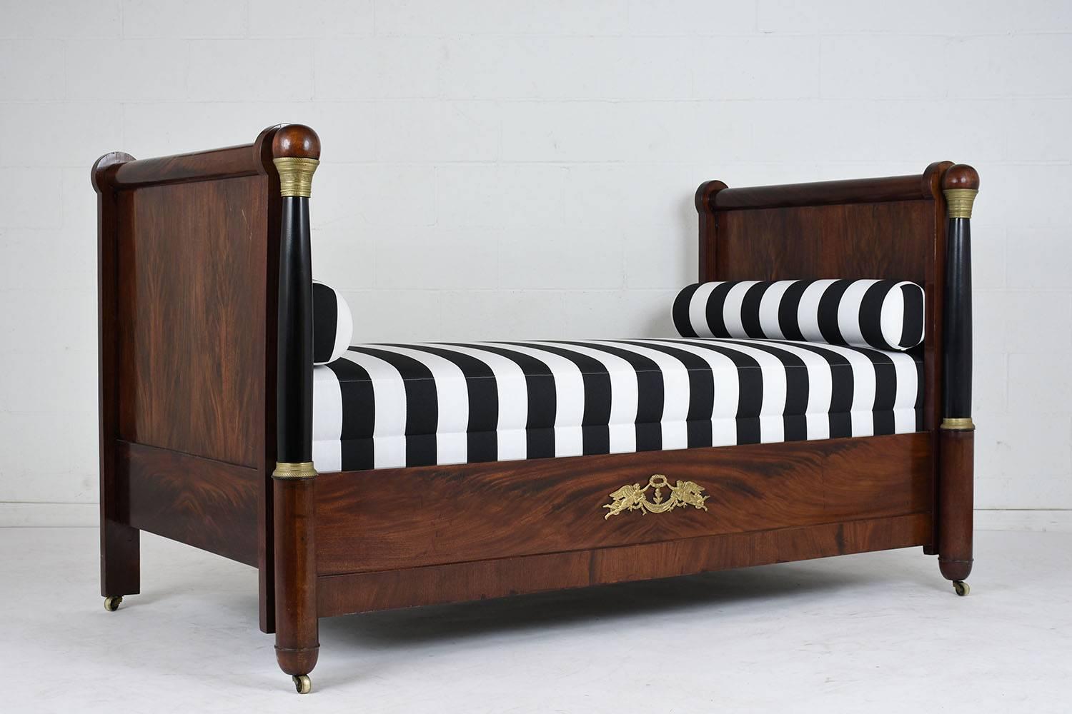 This Stunning 1840's French Empire-style Daybed has been completely restored, the frame is made out of mahogany wood and is stained a rich mahogany color with black column accents and bronze decor. The daybed features a new comfortable foam cushion