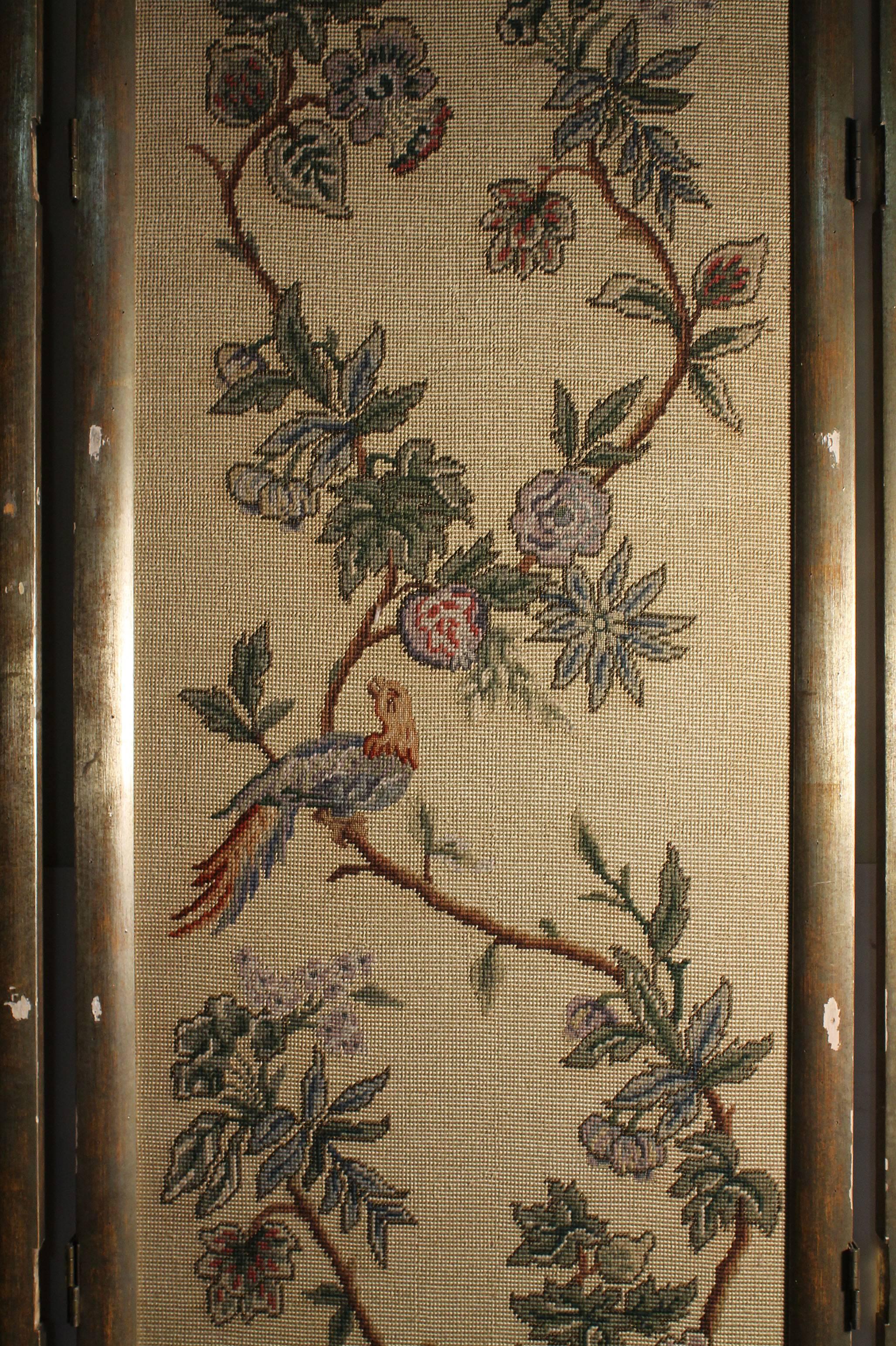 Beautiful vintage Italian chinoiserie or oriental room divider screen with stitched panels of foliage, flowers and birds of different colors. Silver painted sculptural wood frame. Backside is solid fabric color. 
In the manner of James Mont &