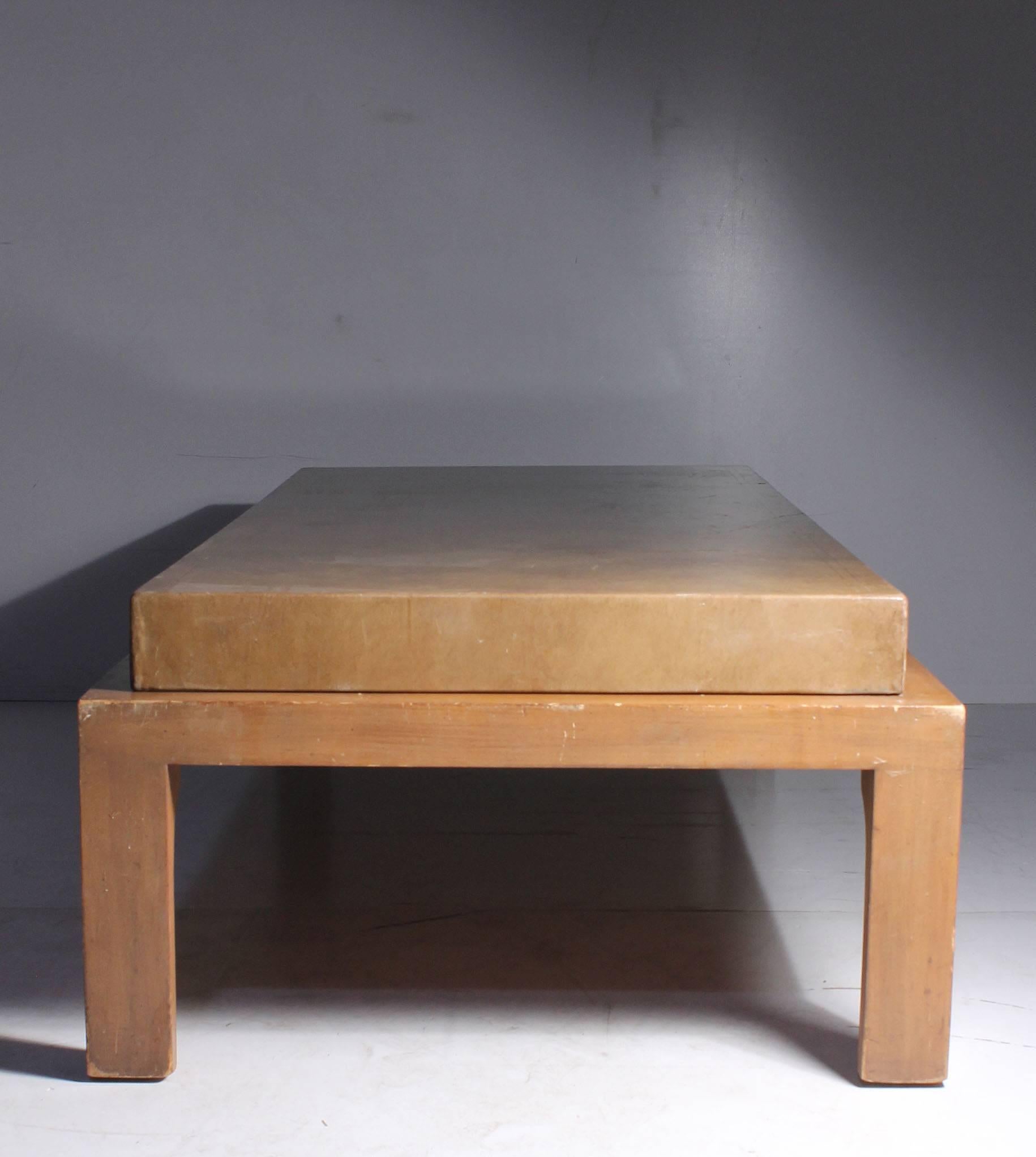 Vintage Mid-Century leather wrapped designer coffee table attributed to Tommi Parzinger. Gold tooling leather wrapped box sits elegantly on a stretcher base. No labels on the piece.  The leg shape is the same form Tommi Parzinger has executed other