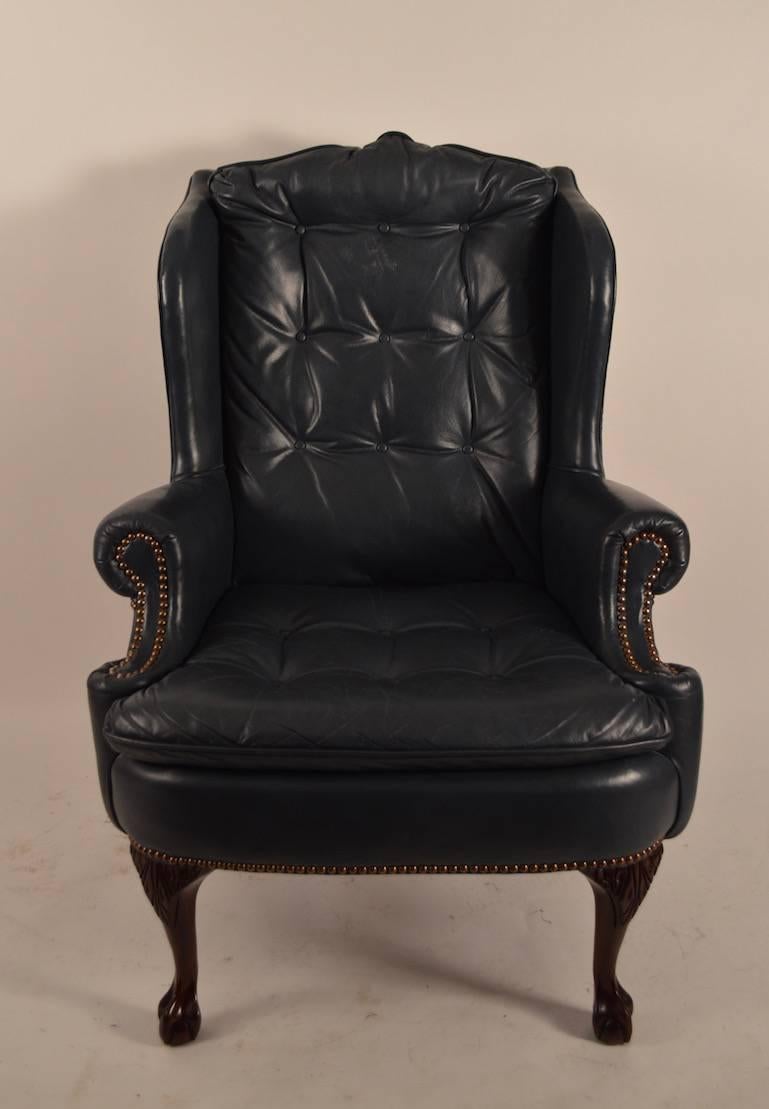 Midnight blue leather wing chair, with carved cabriole legs and ball and claw feet. Clean, comfortable and well constructed. Vintage leather tufted seat and back, studded trim, manufactured by vintage American furniture company 
