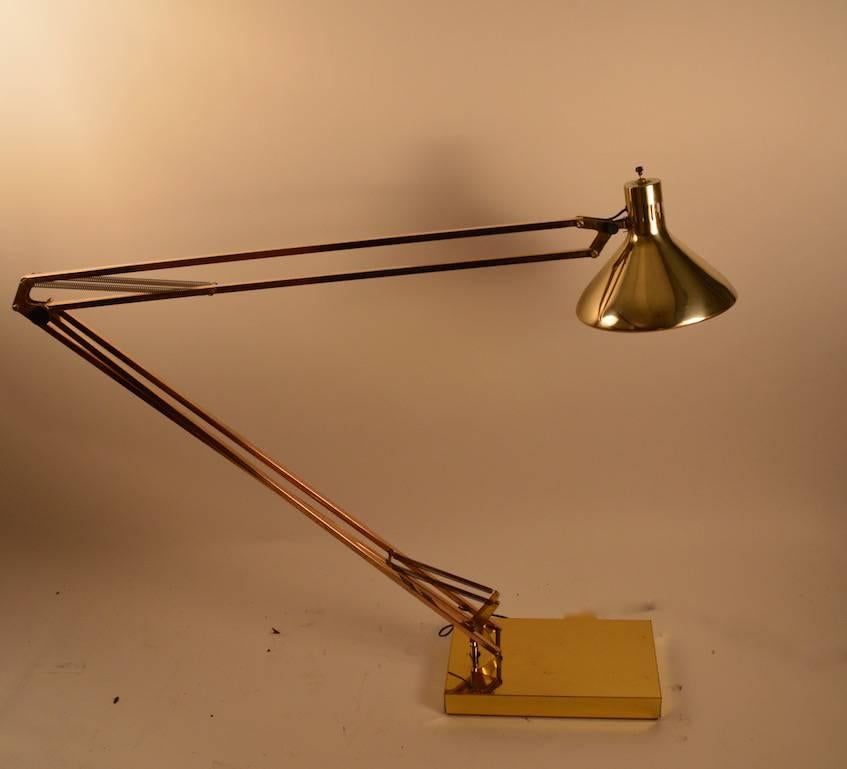 Vintage brass angle poise adjustable floor lamp. This 1970s vintage example can adjust up, down, and pivots on the base, as well as having a pivot adjustment on the metal hood shade. Shade 10