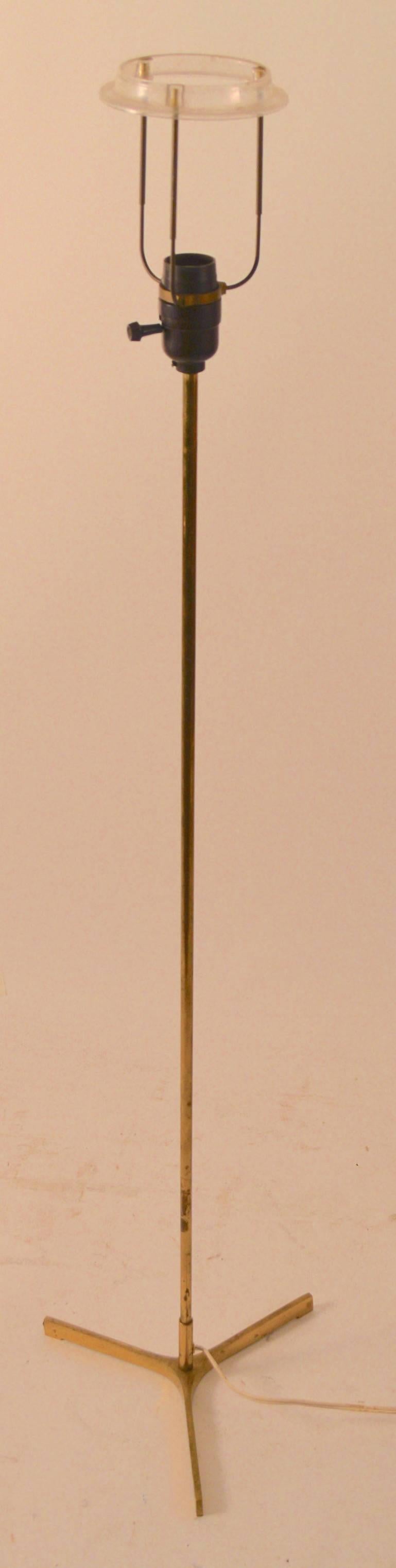 Elegantly proportioned brass floor lamp with tri-part foot. Original shade included for template, shade has stains etc. Brass finish shows wear, and tarnish.