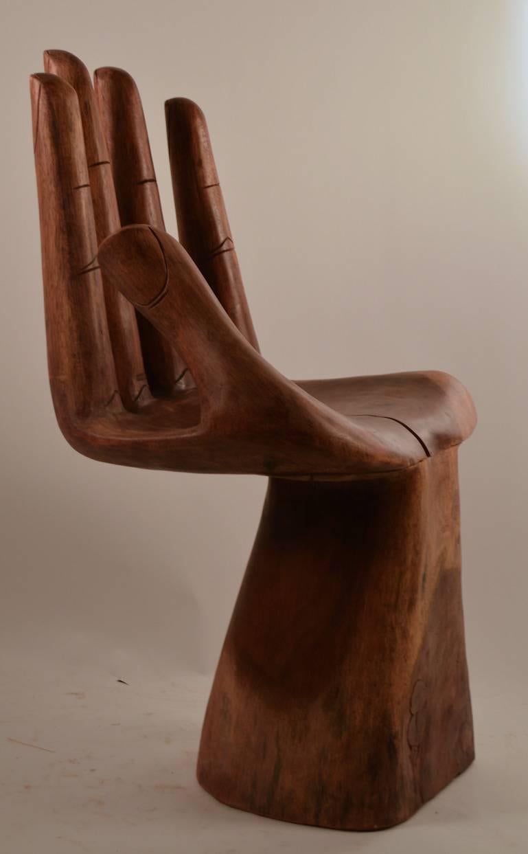 Solid mahogany carved wood hand chair, period example, after Pedro Friedman. 
Finish shows wear and there is a split in the palm, as shown. Structurally sound, solid and extremely stylish item.