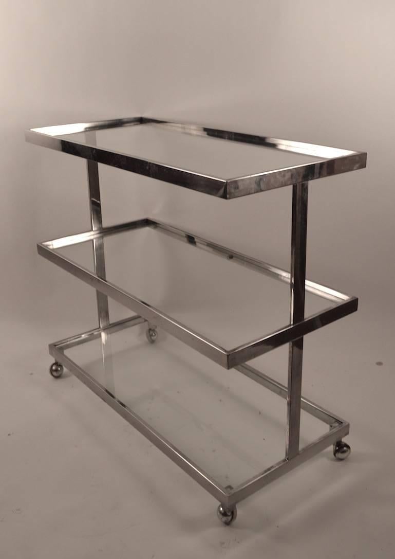 Unusual three-tier chrome frame service, bar cart. Rectangular glass shelves rest in chrome frame. Classic Art Deco Revival design circa 1970s.