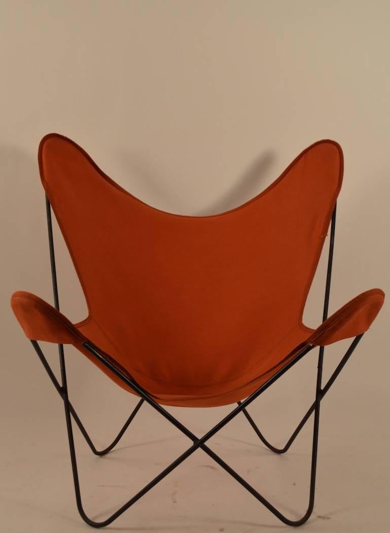 Hip sling chair with vintage orange canvas sling seat, on wrought iron frame.