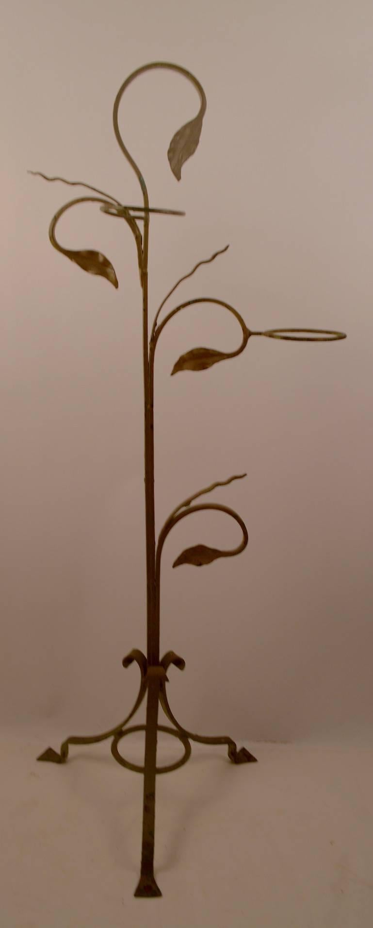 Wrought iron freestanding plant stand by Salterini. This example hold two flower pots, and is in old tan paint finish, paint shows wear, normal and consistent with age.