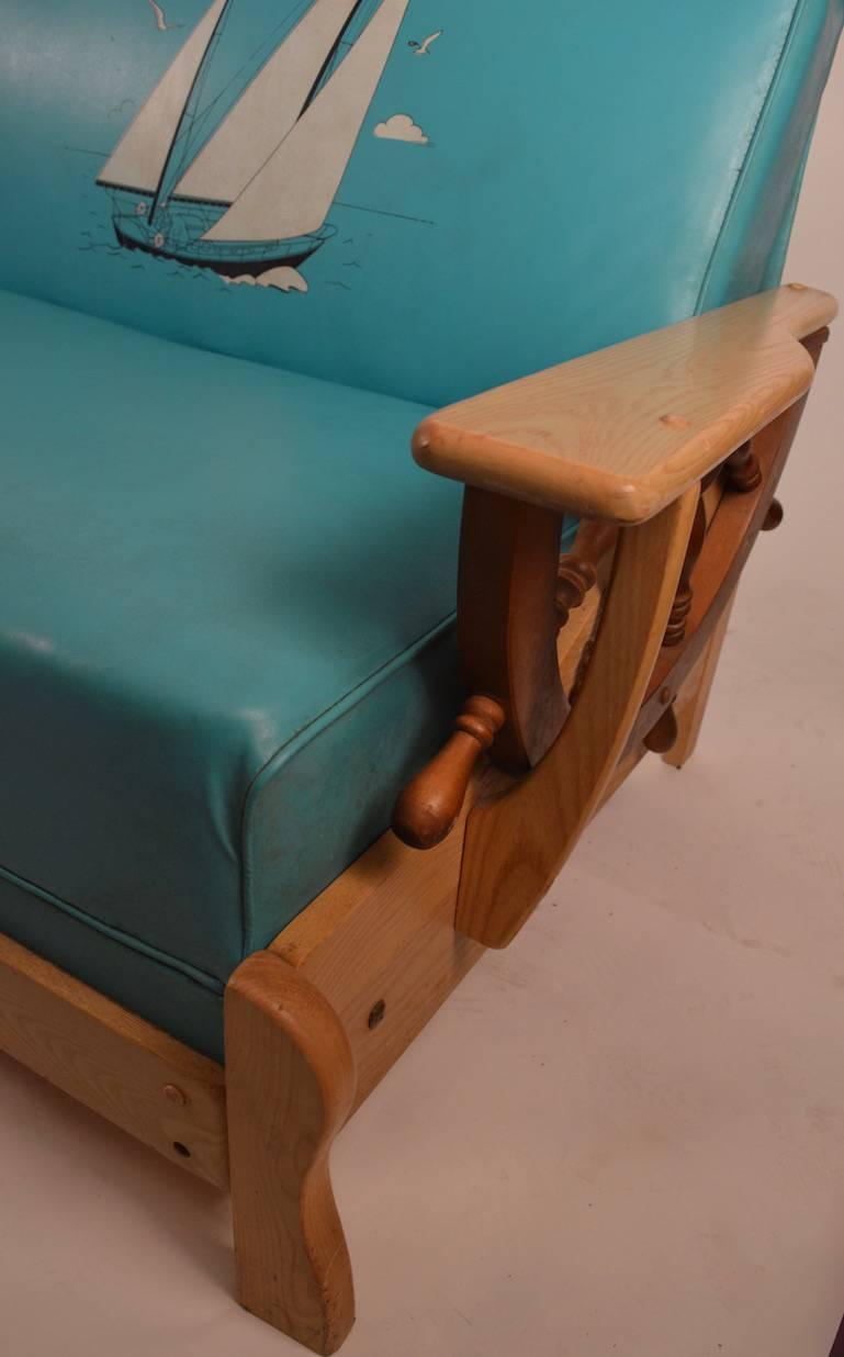 Interesting nautical theme sofa in turquoise vinyl with sailboats; the frame also has nautical reference decorations, an anchor, ships wheel arms etc. This sofa folds flat to become a bed, perfect for a rec. room, spare bed etc.
 The sofa is in