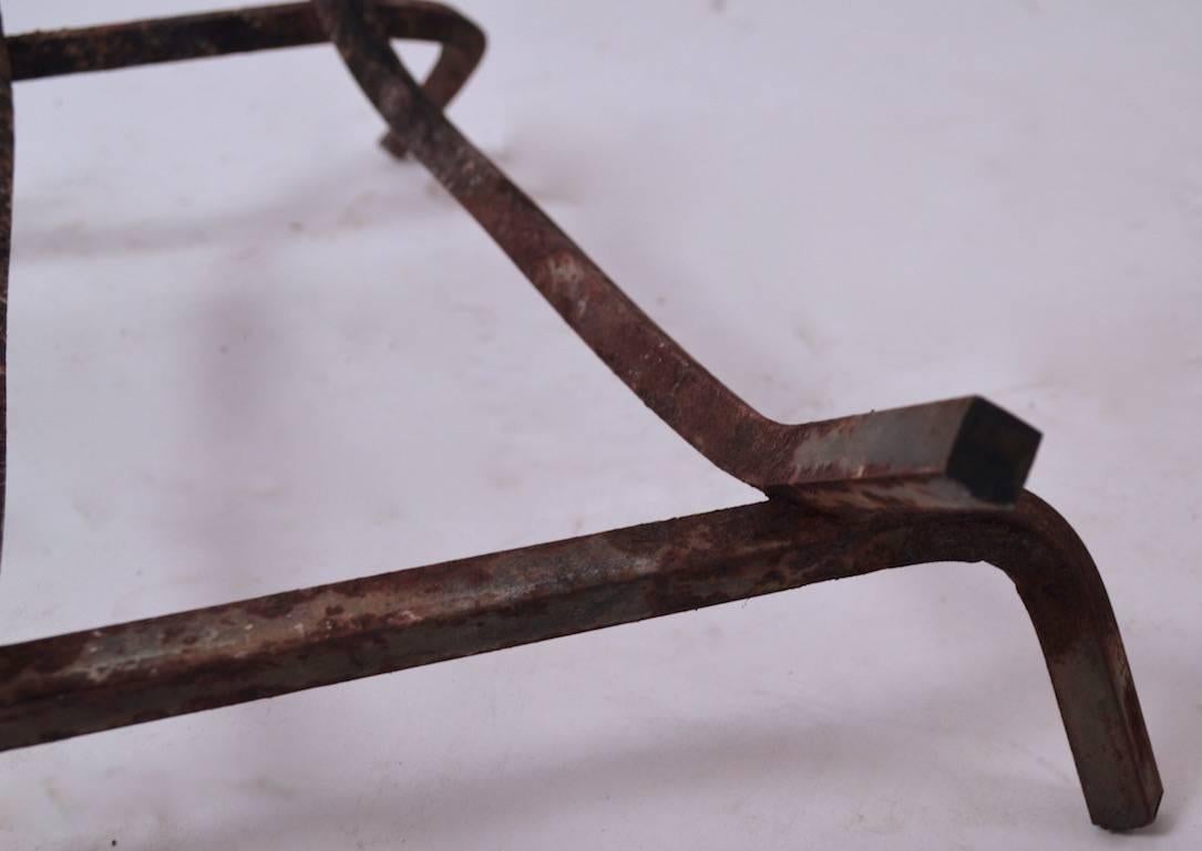 Squared iron elements form the log holder and legs, welded construction, rust patina consistent with use.