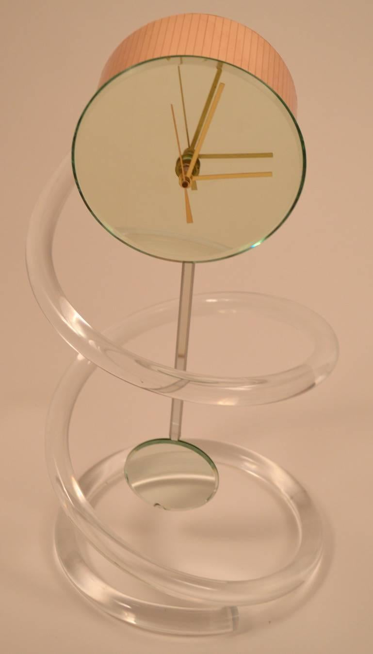 1990s John Gilmore battery operated pendulum clock. The clock is mounted on a tubular Lucite spiral support, mirrored pendulum (small blemish on pendulum).
 Working, clean, original condition. Clock 5.75