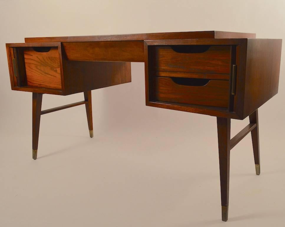 Stylish desk by Sligh Lowry, flanking tambour roll cabinets open to reveal desk drawers, under raised writing surface.
The left side opens to a file drawer, right side opens to two storage drawers, with large centre drawer.
Splayed legs with metal
