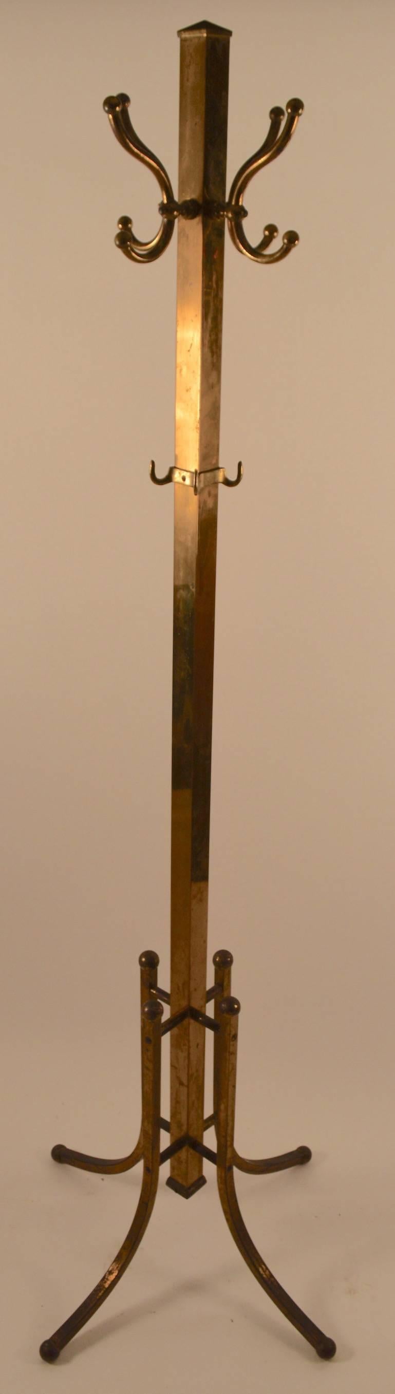 Squared brass vertical standard with four coat/ hat hooks at the top, and four smaller hooks lower on the vertical element for smaller garments. 
 Sturdy and stabile turn of the century freestanding coat tree stand. Width at top 10.5