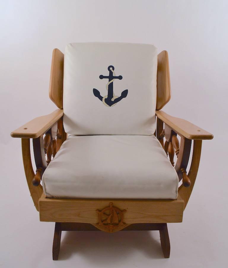 Mid-Century nautical theme platform rocking chair. The chair has loose vinyl cushions, the back cushion having an anchor motif, the wood frame has ships wheel arm supports and a nautical decoration in the front, as shown. Measures: Arm height 21.5