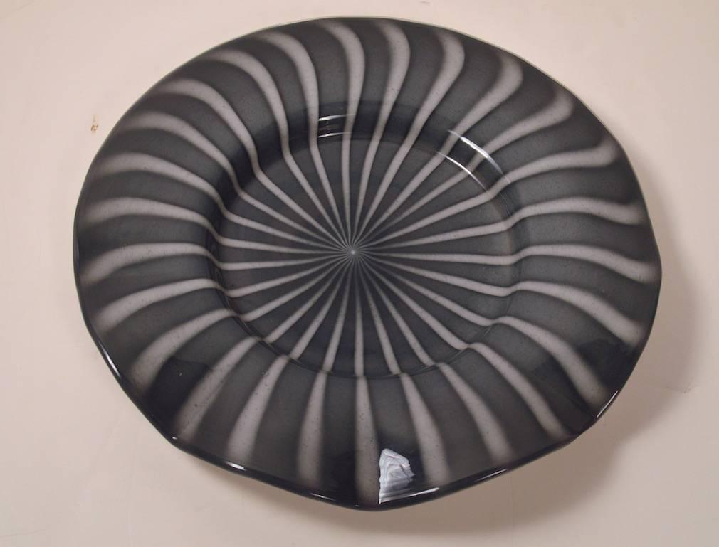 Dieser beeindruckende Teller aus Muranoglas weist alle Merkmale von Alfredo Barbini auf, ist jedoch unsigniert. 
 Die Oberseite ist grau und weiß gestreift, die Unterseite ist weiß, mit einem polierten Zapfen. Dies ist die größte Muranoplatte, die
