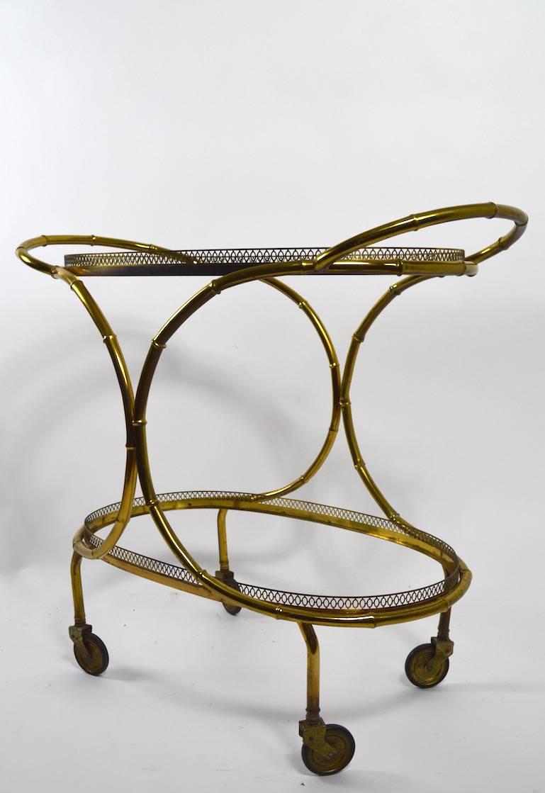Very chic and stylish serving cart, faux bamboo brass structure, with plate glass trays.
Unusual and sexy form, very good original condition.
Width of oval tray surface 28