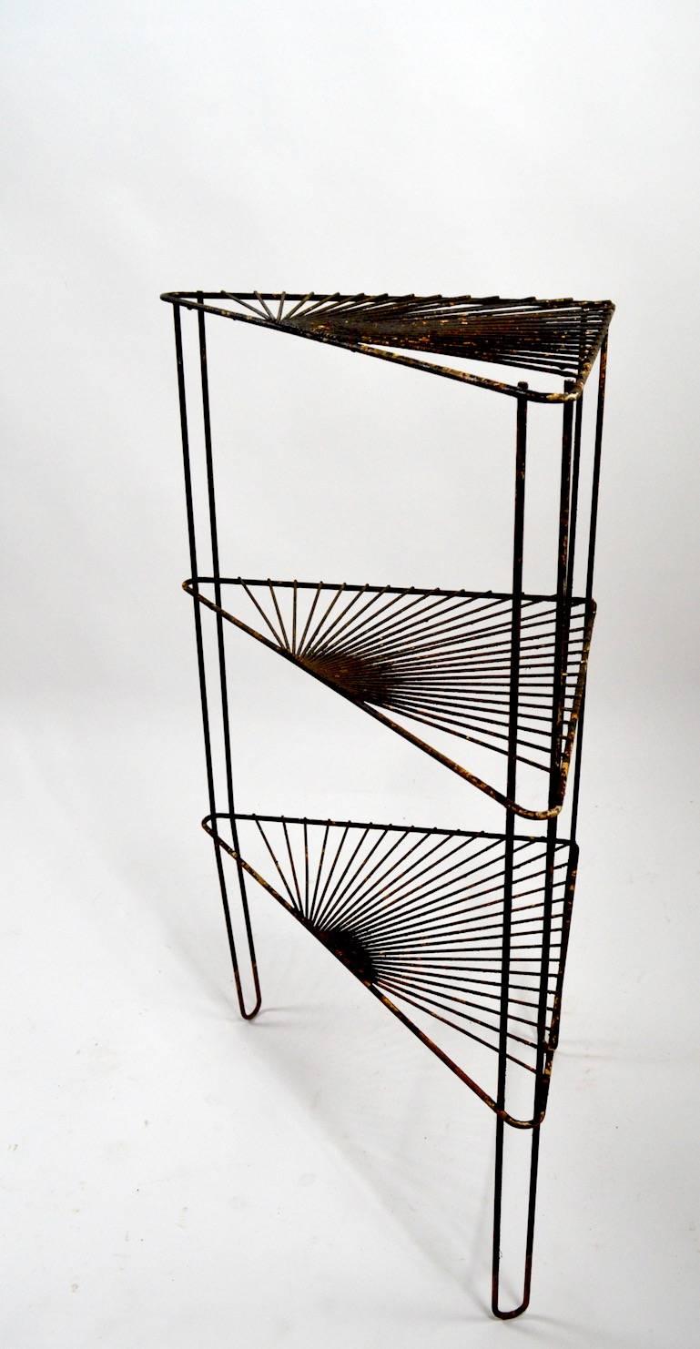 Interesting wrought iron stand having three triangular shelves each consisting of radiating iron rods. Currently in old black paint finish, which shows wear, custom powder coating available. Suitable for indoor or outdoor use.