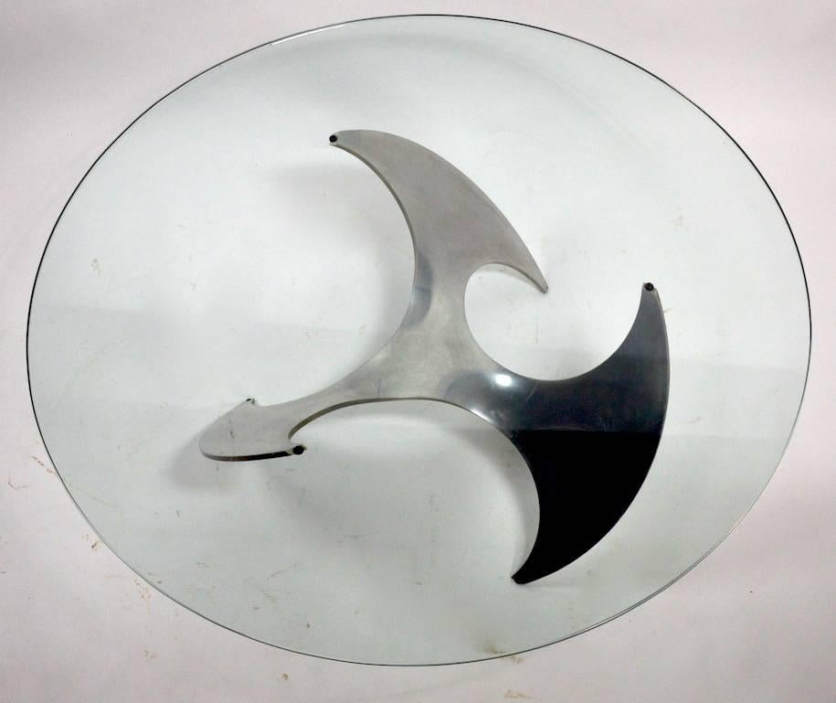 Solid aluminum propellor form base supports round glass top (shows extremely minor pin flakes along outer edge, inconsequential). Classic German Modernist design, clean ready to use.