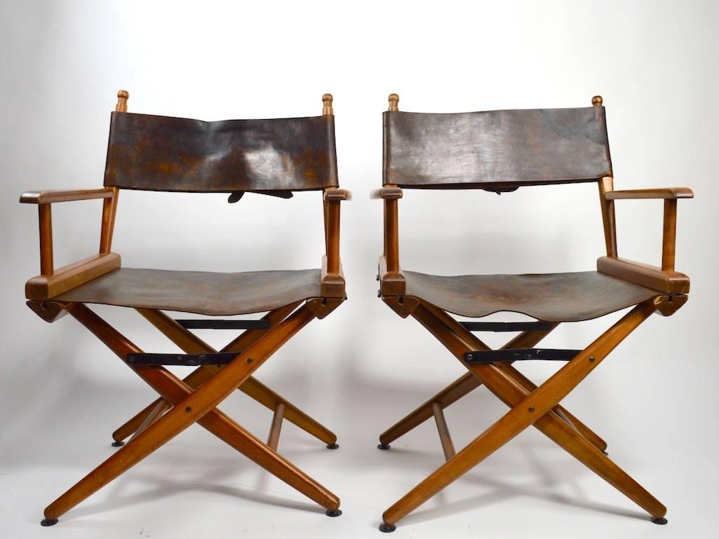Extraordinary pair of folding wood and leather Campaign, Directors chairs in nice original condition. These chairs are usually found with fabric seats and backs, this pair has nicely distressed, original leather seats and backrests, backrests have