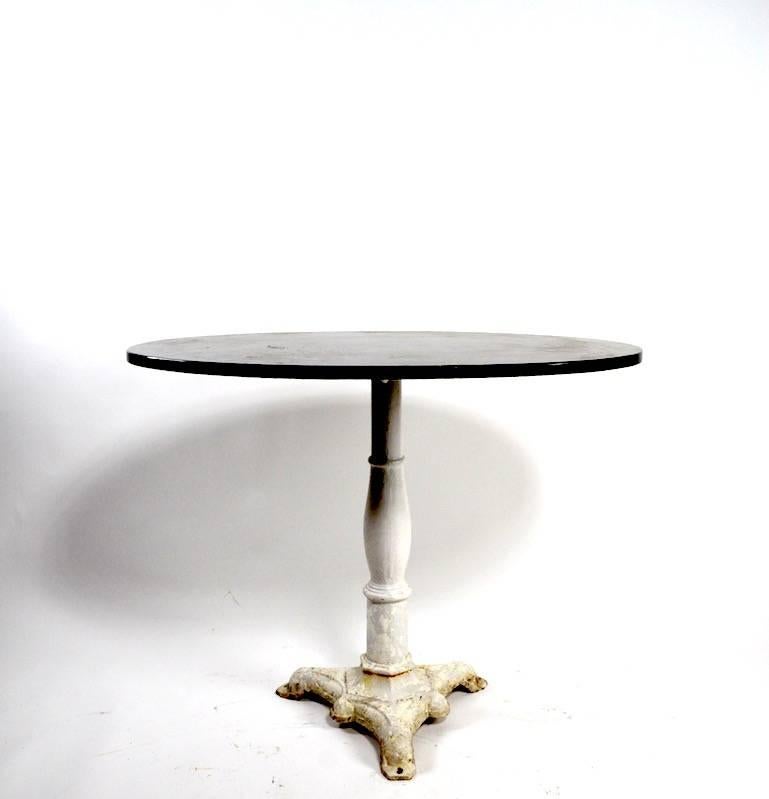 Nice graphic table with oval black marble top and cast iron base in old white paint finish.
