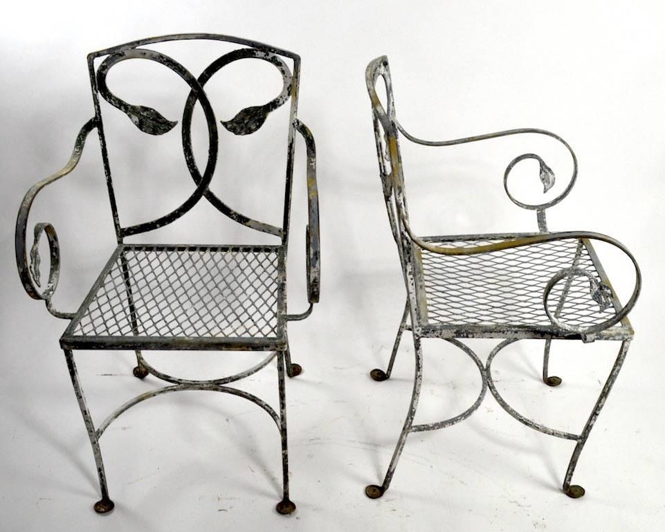 Pair of wrought iron armchairs by Salterini. These chairs have a romantic, organic foliate motif, both show loss to the white paint finish as shown. Both are structurally sound and ready to use as is. We offer custom powder coat finishing if you