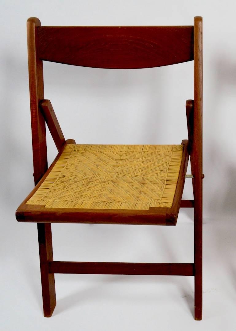 Unusual and rare set of Danish Modern folding chairs with caned seats. As expected with Danish made furniture these four chairs are very well designed and constructed. Some caning shows minor loss, as shown. Chairs are clean and usable as is.