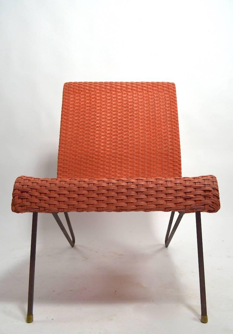 Chic scoop chair in peach colored coated wicker, on wrought iron legs. Original, clean, ready to use condition, showing only very light cosmetic wear normal and consistent with age.