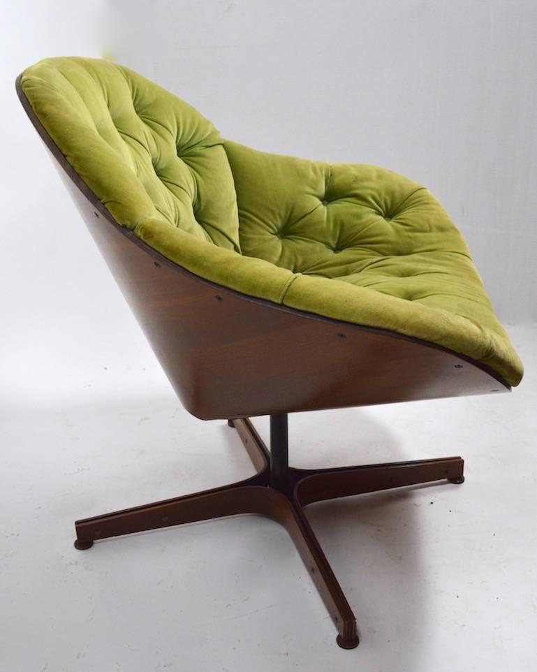George Mulhauser for Plycraft swivel lounge chair. This is a rare, not often found form. This example shows some cosmetic wear, including a small veneer chip on the base, small scratch on the back, and the upholstery shows significant wear.