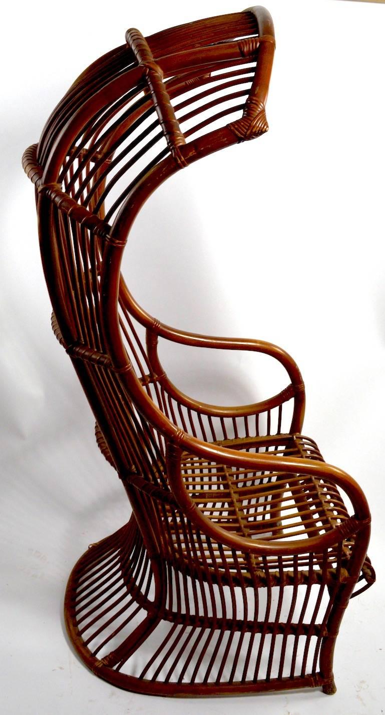 Dramatic high back hood form bamboo and reed wicker chair. Unusual, graphic architectural chic lounge chair, selling without cushion. This example shows some minor wear, specifically missing one section of reed at the seat, and one at the bottom