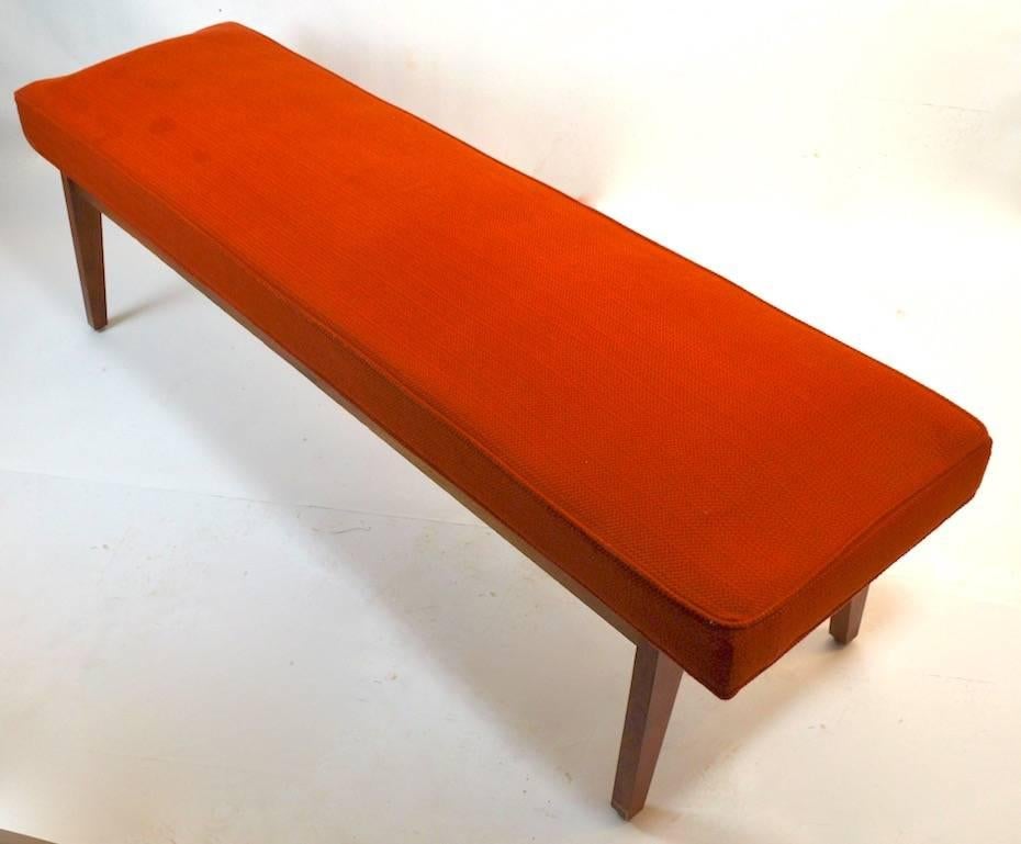 Classic midcentury bench with solid wood base and upholstered seat. The seat shows some wear, usable as is but would benefit from reupholstery. The wood base shows some cosmetic wear to the finish, use as is or refinish to perfection if you prefer.