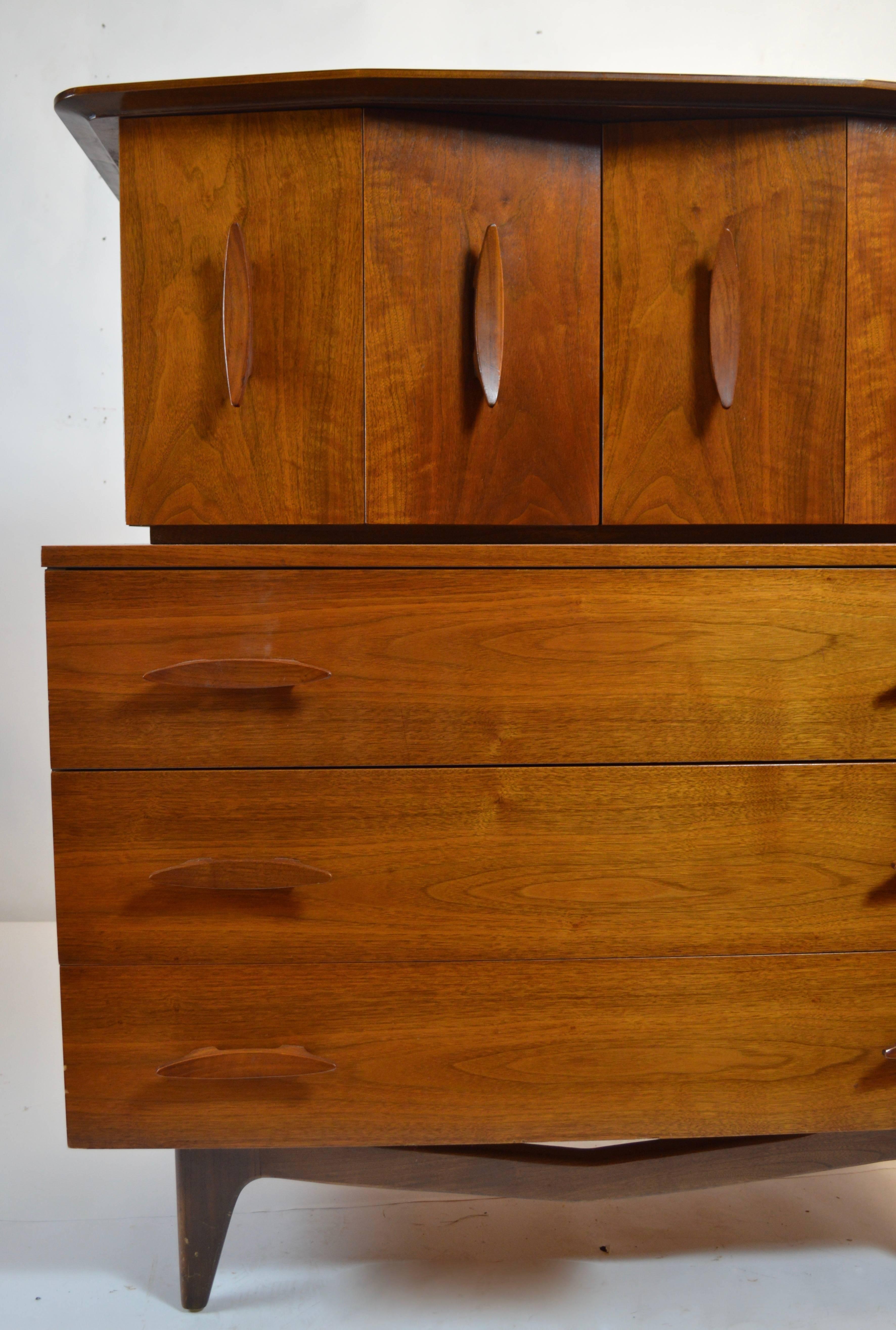Stylish chest on chest form gentleman's dresser, having folding doors on top which open to revel four large interior drawers, and three oversized drawers on the bottom. This chest has ample storage and is in very good original condition, showing