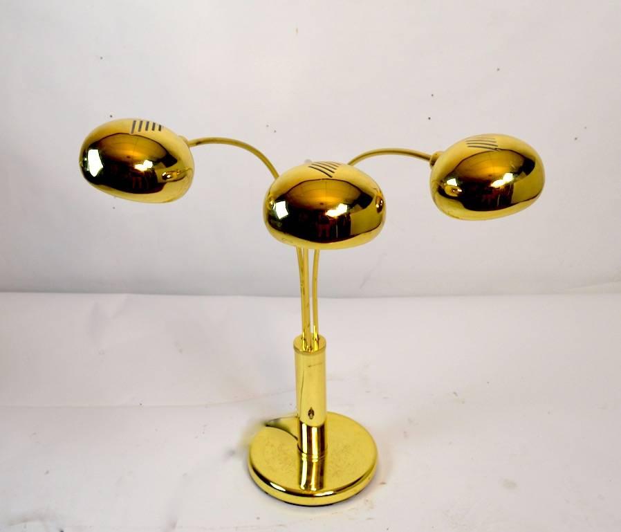 Cool mod style three-light arc lamp in brass, unusual smaller scale, tabletop, desk lamp size. Each light can be operated independently or lit as a group, the arms will swing to adjust position and direct light as needed. The finish shows some